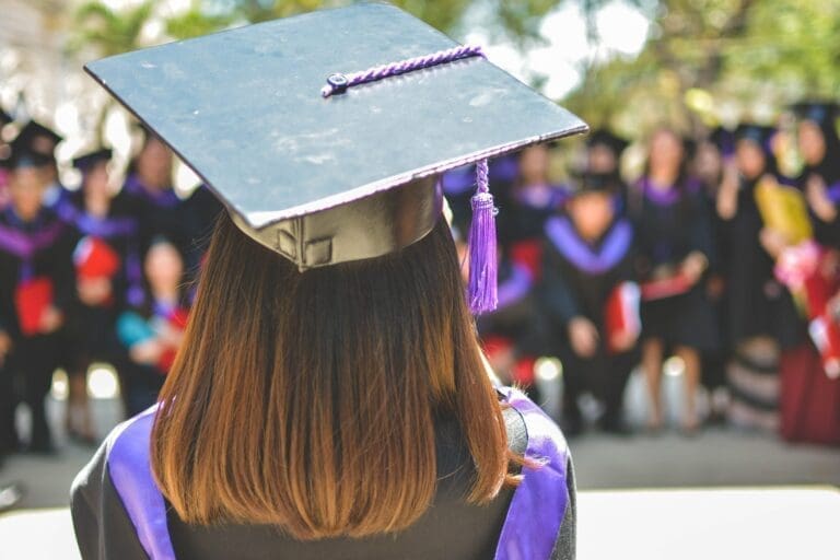 A graduate picture from the back. There is a moment in a purple gown with a black On and purple castle