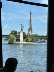 A miniature replica of The Statue of liberty alongside the Eiffel Tower from a riverboat. One of Elizabeth's photos. I think